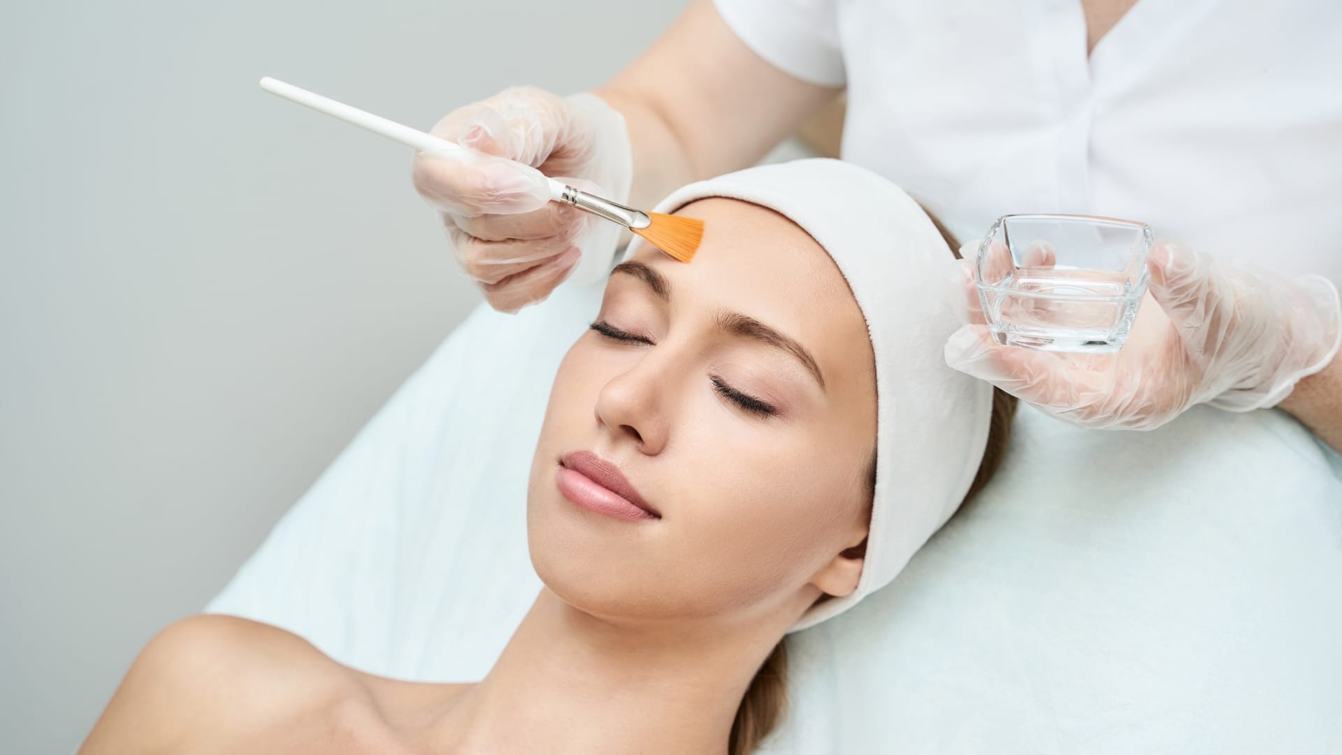 A young woman is undergoing a facial chemical peel treatment.